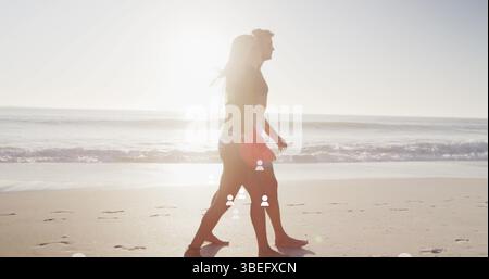 Image de plusieurs icônes de profil flottant au-dessus d'un couple caucasien marchant ensemble à la plage Banque D'Images
