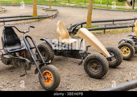 Divers karts sont stationnés sur une piste de terre dans une zone de loisirs, entourée d'herbe et d'arbres. Le cadre suggère une atmosphère accueillante pour Banque D'Images