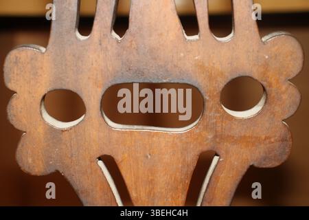 Le dossier sculpté d'une chaise en bois. Le bois a un ton brun chaud avec un grain visible et une certaine usure, suggérant l'âge ou une utilisation fréquente. Banque D'Images