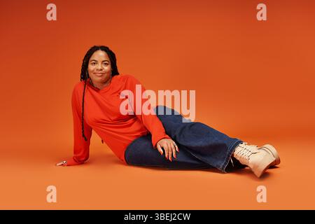 Une femme confiante avec des tresses salons dans une tenue décontractée qui rayonne de joie et d'énergie. Banque D'Images