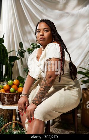 Une belle femme afro-américaine dans une robe d'été rayonne de confiance parmi les plantes vertes vibrantes. Banque D'Images