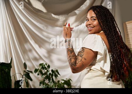 Une belle femme avec des tresses rayonne de joie tout en posant dans une robe d'été entourée de verdure. Banque D'Images