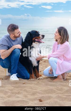 Portrait de couple caucasien avec chien en vacances à la plage souriant à la caméra Banque D'Images