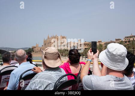 Groupe de touristes chevauchant sur le pont supérieur d'un bus touristique admirant et photographiant la cathédrale de la Seu, point de repère important de la ville, Majorque Banque D'Images
