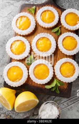 Les cookies combinent deux couches de biscuits Shortbread au beurre et un gros plan de remplissage de citron acidulé fait maison sur une planche de bois sur la table. Haut vertical vi Banque D'Images
