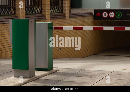Barrière d'entrée automatique au garage souterrain moderne avec système de sécurité, panneau de charge de véhicule électrique et symbole de restriction de hauteur Banque D'Images