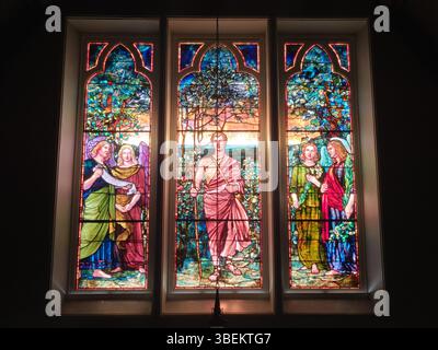 Les trois panneaux supérieurs de la fenêtre commémorative William Breese de l'église épiscopale Mary's-in-Tuxedo, créée par Tiffany & Co, sont un bel exemple de l'art des vitraux du début du XXe siècle, avec des motifs complexes et des couleurs vives. Banque D'Images