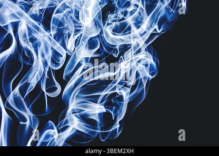 La fumée bleue tourbillonne. Formes abstraites de mouvements doux. Vapeur artistique sur fond sombre. Des courbes créatives ressemblant à une flamme. Mystérieuse énergie qui coule. Banque D'Images