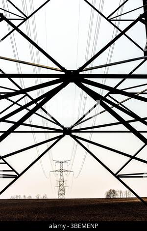 Un poteau électrique haute tension se dresse en bonne place dans un domaine en expansion en Auvergne Rhône Alpes, France. Banque D'Images