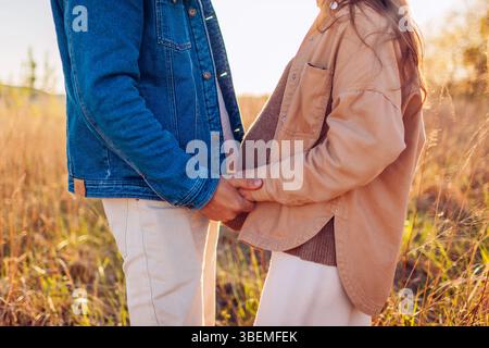 Futur père et mère se tenant la main. Couple de famille enceinte marchant à l'extérieur au coucher du soleil. Parentalité Banque D'Images