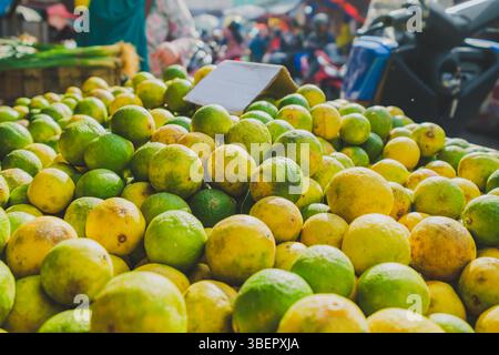 Balikpapan, Indonésie – 19 avril 2025. Gros plan de citrons verts et jaunes mûrs exposés dans un marché de rue traditionnel. Banque D'Images