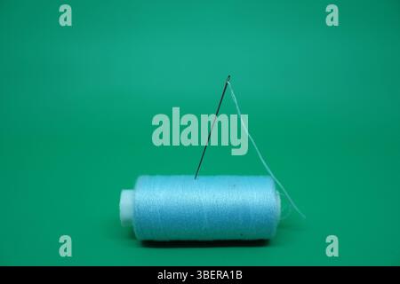 Aiguille à coudre coincée dans le fil. Banque D'Images