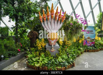 Singapour, Singapour - 4 avril 2025 : sculpture décorative de serpent à plusieurs têtes entourée de fleurs tropicales et d'orchidées dans la forêt des nuages, jardins Banque D'Images