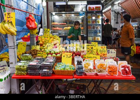 Singapour, Singapour - 4 avril 2025 : étal de fruits local dans Little India avec des produits tropicaux colorés et des panneaux manuscrits dans une rue animée Banque D'Images