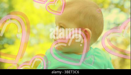 Image de cœurs tombant au-dessus du bébé heureux caucasien Banque D'Images