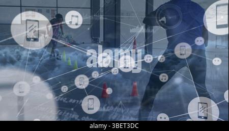 Image d'un réseau d'icônes numériques et de nuages sur un joueur de football afro-américain pratiquant Banque D'Images