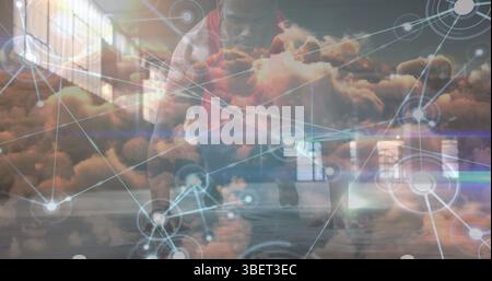 Réseau d'icônes numériques au-dessus des nuages dans le ciel contre l'homme de forme afro-américain effectuant des pompes Banque D'Images