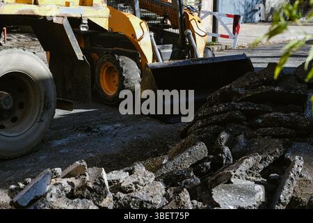 Scène des travaux publics montrant Une grande machine jaune collectant des débris de rue pendant l'entretien de la route Banque D'Images