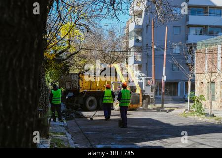 Des ouvriers de la construction vus de derrière regardant Un camion ramasser les débris de la rue pendant les travaux publics à Rosario, en Argentine. Paver les rues de la ville Banque D'Images