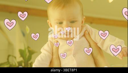 Image de cœurs tombant sur le bébé heureux caucasien heureux Banque D'Images