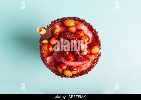 Petit verre fou, un mélange d'ingrédients sucrés, salés et épicés isolé sur fond bleu. Snack typique du Mexique. Banque D'Images