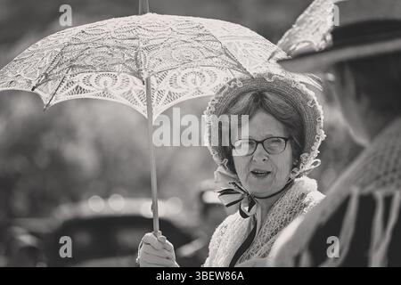 Femme âgée dame dans la robe ancienne historique, tenant le parasol parapluie en dentelle, noir et blanc vintage monochrome Banque D'Images