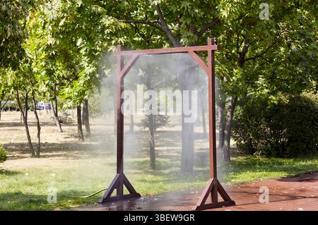 Cadre de pulvérisation d'eau pour le refroidissement par temps chaud sur la rue de la ville à Kiev, Ukraine. Système de brouillard de refroidissement par brouillard d'eau dans le parc de la ville en été chaud. Protection aga Banque D'Images