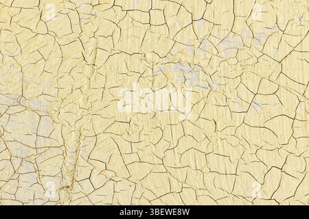 Vue rapprochée de la peinture jaune fissurée révélant une surface texturée. Représente le vieillissement, la pourriture et la beauté dans l'imperfection. Convient pour les arrière-plans, art. Banque D'Images