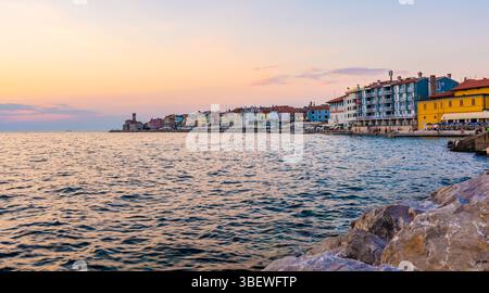 Coucher de soleil au-dessus de la mer adriatique dans la ville de Piran, Slovénie. Vieille ville ancienne et médiavée, vue de la côte et du port. Vieilles pierres en premier plan, belles Banque D'Images