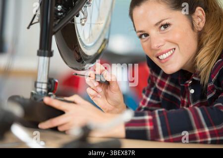 heureuse jeune femme réparant son vélo Banque D'Images