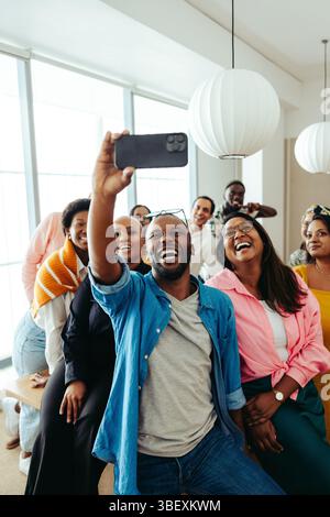 Un groupe diversifié de professionnels se réunit pour prendre un selfie joyeux, rayonnant d'enthousiasme et de positivité. L'image capture les sourires et la camaraderie, ID Banque D'Images