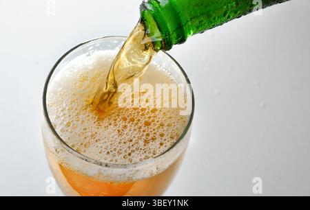 Détail du verre rempli de boisson mousseuse de bouteille en verre vert et fond isolé blanc. Vue de dessus. Banque D'Images
