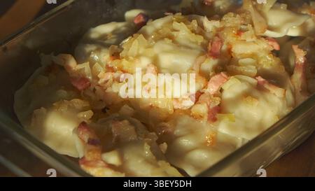 Pierogi polonais avec oignon frit et bacon – boulettes maison traditionnelles dans un plateau en verre, capturées en plein soleil, gros plan Banque D'Images