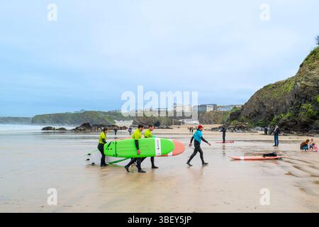 Un instructeur de surf de l'Escape Surf School marchant avec un groupe de surfeurs débutants sur la plage de Towan à Newquay en Cornouailles au Royaume-Uni. Banque D'Images