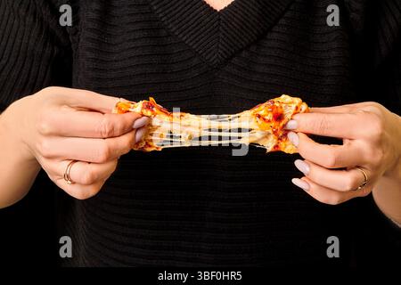 Femme étirant le fromage fondu de délicieuse tranche de pizza Banque D'Images