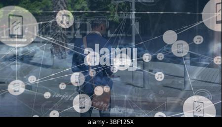 Réseau d'icônes numériques sur des nuages contre un homme d'affaires afro-américain marchant dans la rue Banque D'Images