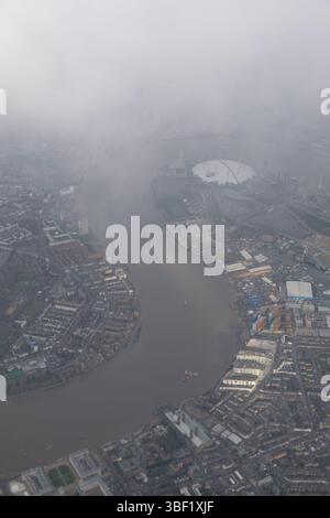 Vue aérienne de Londres, Royaume-Uni, par une journée brumeuse. La Tamise serpente à travers la ville, avec l'O2 Arena visible au loin. Banque D'Images