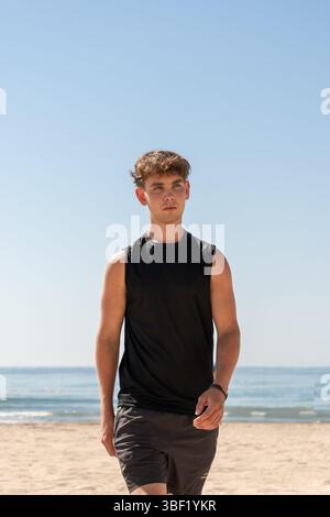Jeune homme actif marche le long de la plage au soleil Banque D'Images