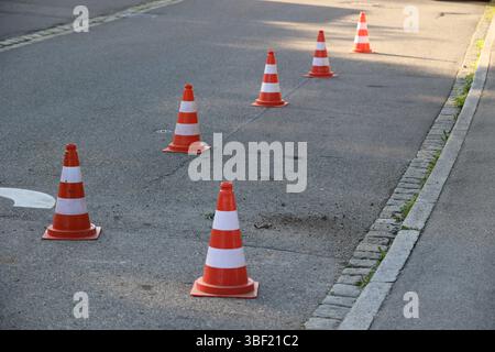 Une rangée de cônes orange et blanc sont alignés sur une rue Banque D'Images