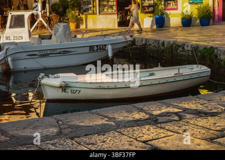 Veli Losinj, Croatie-25 juillet 2024 : beau bateau de pêche en bois ancré dans le port de la ville de Veli Losinj, Croatie au coucher du soleil Banque D'Images