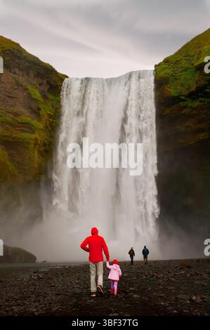 La cascade de Skógafoss plonge spectaculairement sur les falaises anciennes, sa puissante brume s’élevant contre le ciel – un symbole à couper le souffle de la nature islandaise Banque D'Images