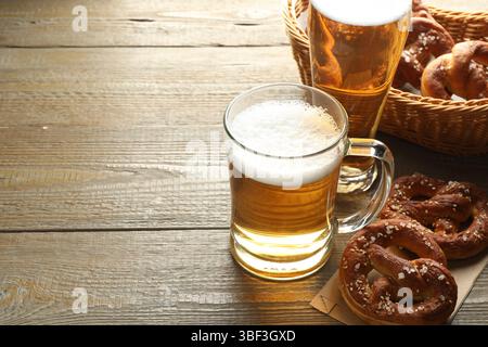 Délicieux bretzels et tasses en verre de bière sur la table en bois, gros plan. Espace pour le texte Banque D'Images