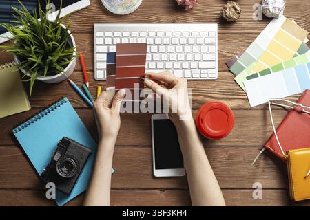 Concepteur Web choisissant des couleurs à partir de nuances au bureau en bois. Bureau vue de dessus avec clavier d'ordinateur et papeterie. Conception de l'interface utilisateur o Banque D'Images