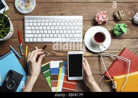 Concepteur Web choisissant des couleurs à partir de nuances au bureau en bois. Bureau vue de dessus avec clavier d'ordinateur et papeterie. Conception de l'interface utilisateur o Banque D'Images