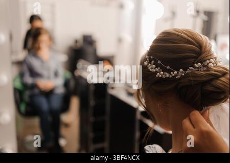 Une mariée reçoit la coiffure professionnelle avec un élégant updo orné d'accessoires de perles délicats pendant les préparatifs de mariage, un doux, roma Banque D'Images