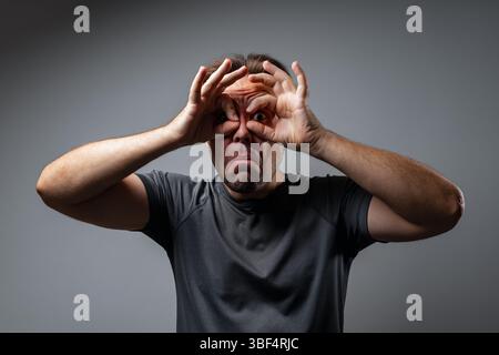 Jeune homme surpris portrait, doigts jumelles geste Banque D'Images