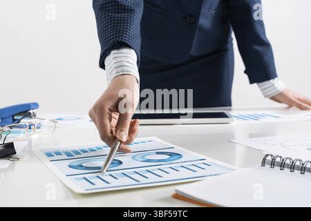 Femme d'affaires debout près du bureau et analysant les graphiques financiers. Directeur d'entreprise réussi dans le costume d'affaires. Gros plan main de femme avec stylo. E Banque D'Images