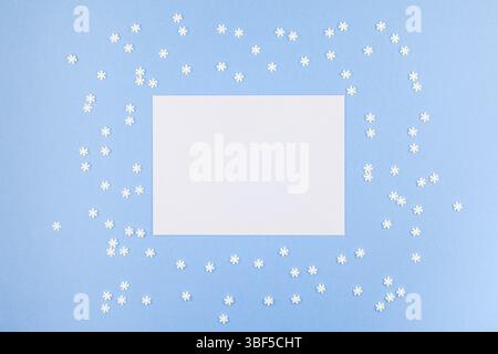 Vue de dessus de la création d'hiver. châssis mise à plat Modèle Maquette Concept fait de petits flocons blancs sur fond bleu pastel enveloppe lettre copie espace minim Banque D'Images