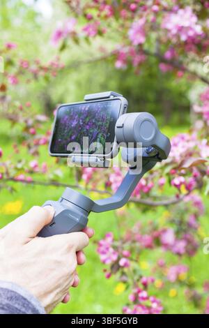 RUSSIE, MOSCOU - 13 MAI 2018 : gros plan de l'homme blogueur mains de tournage vidéo sur smartphone iPhoneX en utilisant un stabilisateur d'image DJI Osmo Mobile dans la broche Banque D'Images