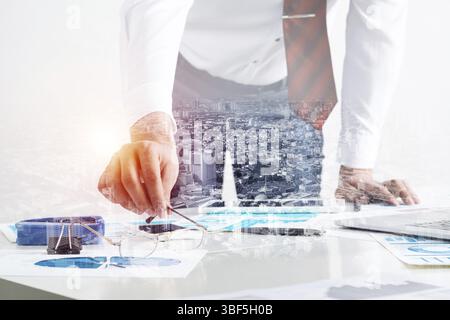Homme d'affaires se tenant près du bureau et analysant les diagrammes financiers. Directeur d'entreprise réussi en costume et cravate d'affaires. Gros plan main homme avec un Banque D'Images